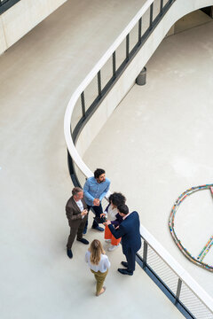 Business colleagues discussing over tablet PC in office corridor