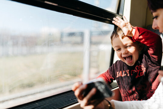 Happy little boy on his first train ride having fun with his mother
