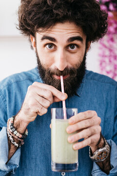Portrait of bearded man drinking green smoothie