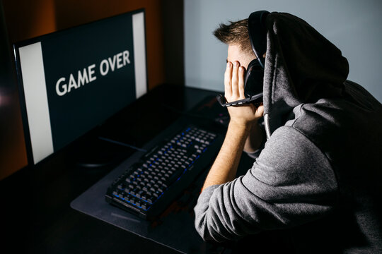 Young man sitting at his PC, looking at screen with game over text