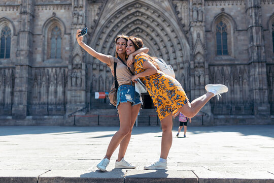 Woman embracing friend while taking selfie through mobile phone standing at Barcelona Cathedral Square in Barcelona, Catalonia, Spain