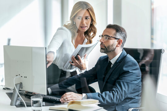 Businesswoman explaining colleague over computer in office