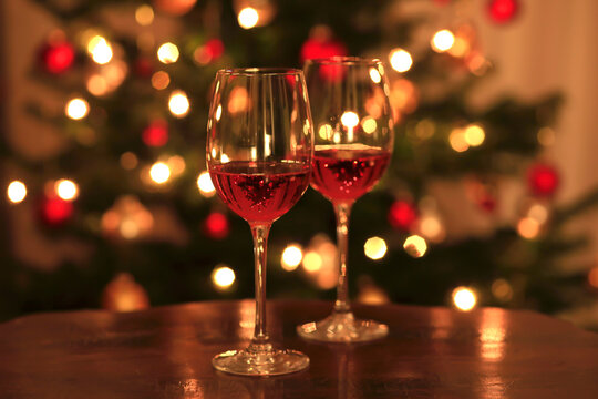 Rose wine in shiny wineglass in front of Christmas tree