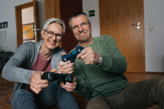 Happy senior couple playing video game at home