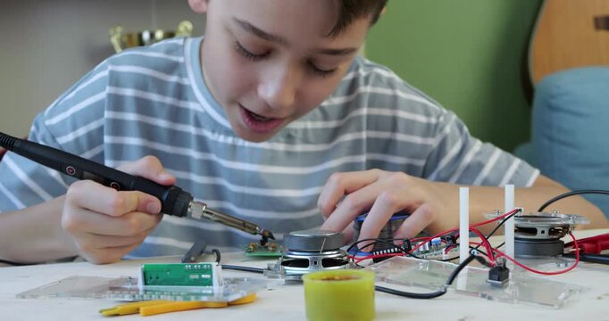 Boy works with soldering iron at home while learning electronics skills. Focused child demonstrates concentration, practical learning and interest in technology and STEM education