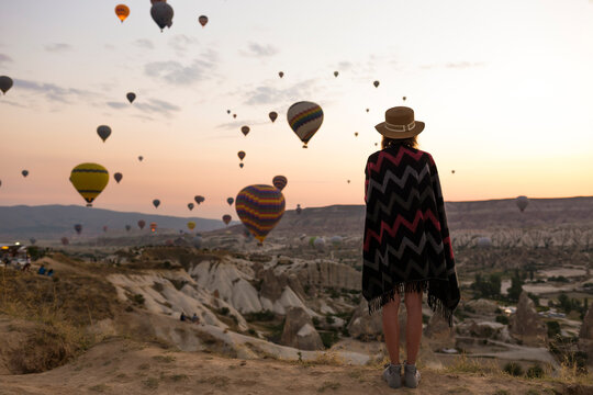 Young woman and hot air balloons in the evening, Goreme, Cappadocia, Turkey
