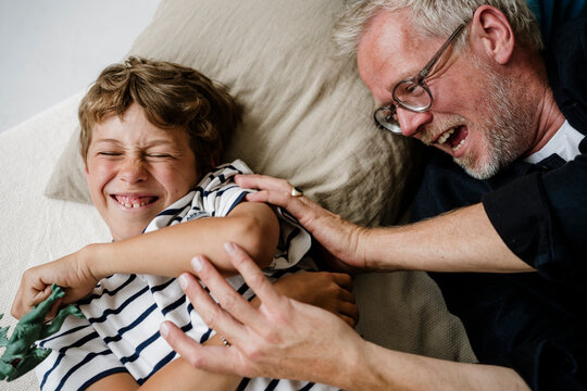 Father and son laughing and tickling each other at home