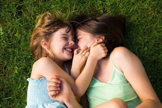 Two sisters lying in meadow having fun