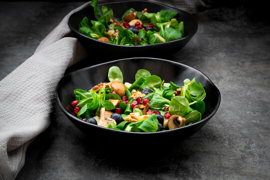 Autumn salad consisting of lambs lettuce, mushrooms, fried pears, blueberries, pomegranate seeds and walnuts