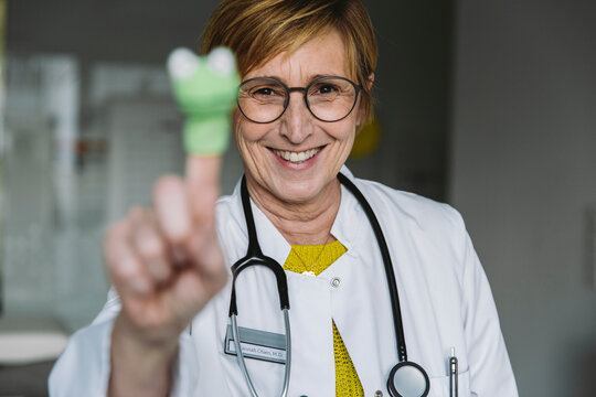 Portrait of happy doctor with finger doll