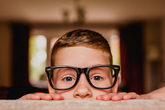 Portrait of peeking boy wearing oversized glasses