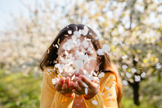 Blowing flower petals from hands outdoors in a spring park