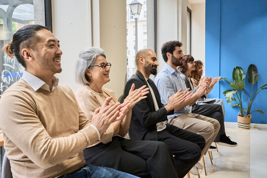 Smiling audience clapping during business presentation in office