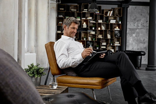 Mature man using digital tablet with digital pen in loft