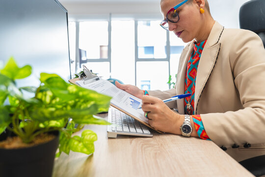 Manager analyzing document on clipboard at the office