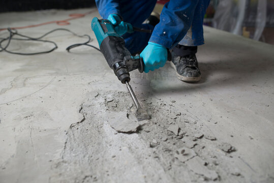 Worker treating the cement floor with a jackhammer