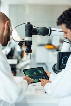 Scientists evaluating medical tablet data in laboratory