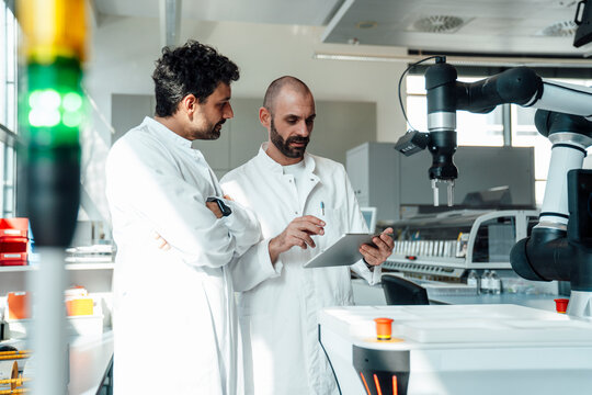 Scientists discussing research with tablet in an automated lab