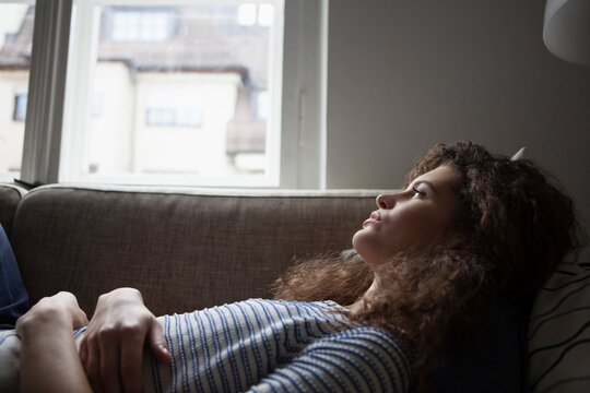 Serious young woman lying on sofa