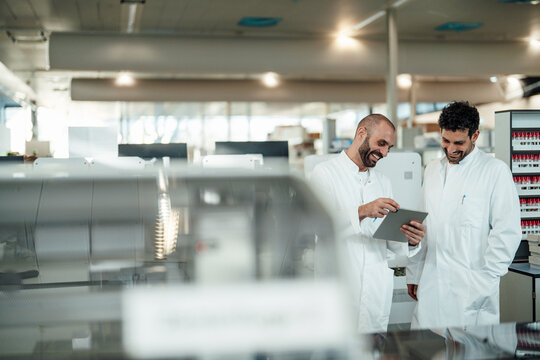 Scientists smiling and discussing research data in laboratory