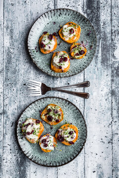 Slices of sweet potato with cream cheese, ramson cream, goat cheese, cress and cranberries