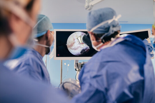 Professionals monitoring surgery on computer screen while standing in operating room