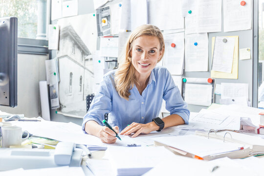 Portrait of smiling woman doing paperwork at desk in office