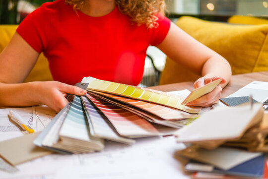 Interior designer choosing color swatch over blueprint in office