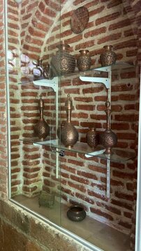 Blue Mosque in Yerevan, Armenia: A collection of vintage copper pots and jugs are artfully arranged on glass shelves within a museum-like setting,