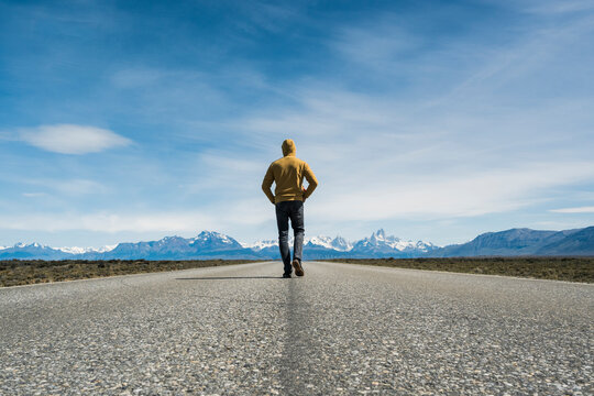 Explorer walking on empty road towards mountain in Patagonia