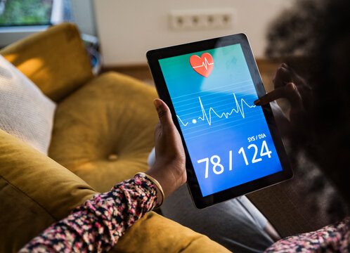 Woman checking blood pressure on a digital tablet at home