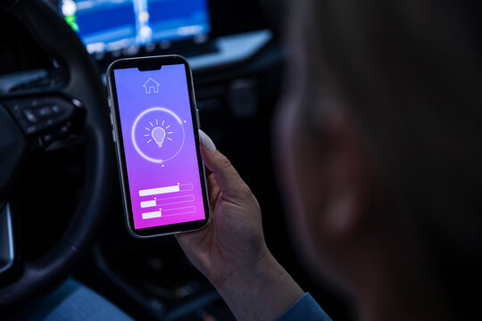 Driver using smarthome app on mobile device in a car at night