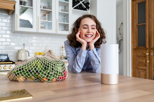 Happy woman with hand on chin looking at smart speaker
