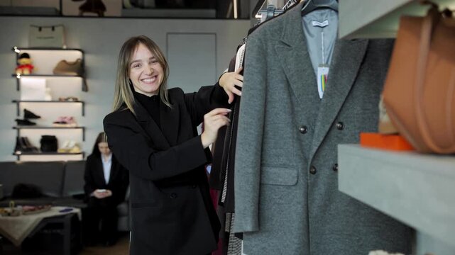 Happy woman choosing clothing items on a rack in a modern retail store, enjoying the shopping experience