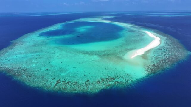 Aerial view of a stunning coral reef with a white sandbank surrounded by turquoise waters and the deep blue Indian Ocean in Kendhoo, Baa Atoll, Maldives.