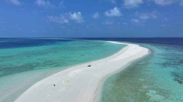 Aerial view of a pristine white sandbank surrounded by turquoise coral reefs and deep blue ocean water under a clear sky in Kendhoo, Baa Atoll, Maldives.