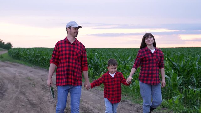 mother father child holding hands, happy people man woman child, Matching Outfits Nature, Family dressed alike, Red checkered shirts, Farm background, Parents and child, Smiling and talking, Walking