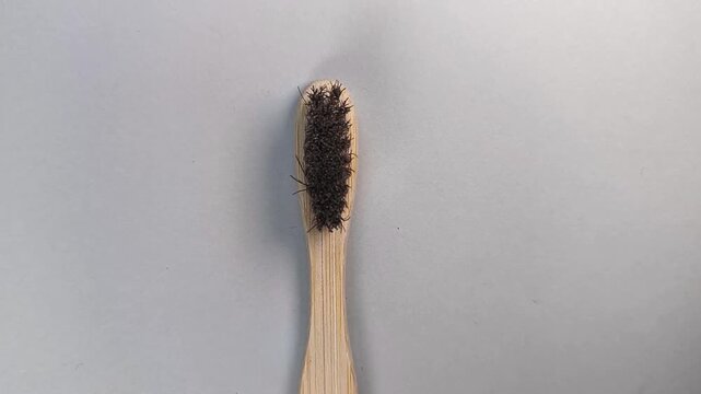 A bamboo toothbrush head is positioned at the lower center of a light gray studio background while the camera slowly zooms in during a product video session to highlight sustainable oral care, natural