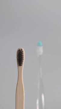 A plastic toothbrush appears in focus in the background while a bamboo toothbrush stands in the foreground, and the camera gradually shifts focus from the plastic product to the bamboo alternative dur