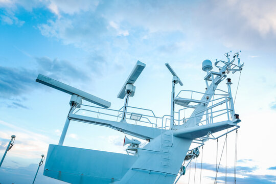 White cruise ship mast with marine radar antennas and satellite communication domes.