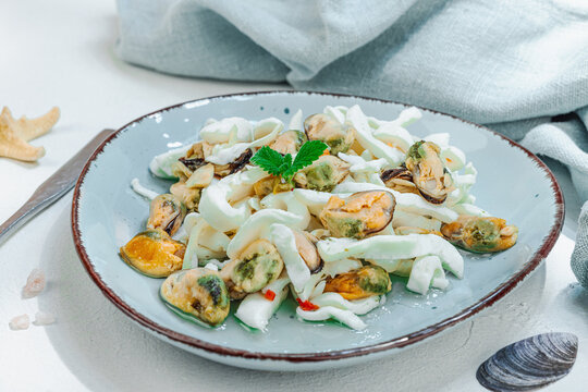 Healthy seafood cocktail salad featuring mussels and squid with starfish and seashells decoration