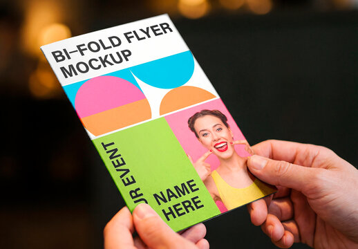Person holding blank card mockup with warm bokeh background