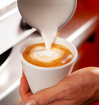Professional barista creating a milk heart on a coffee.