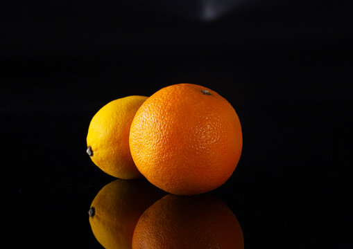 Two oranges on a black background with side lighting.