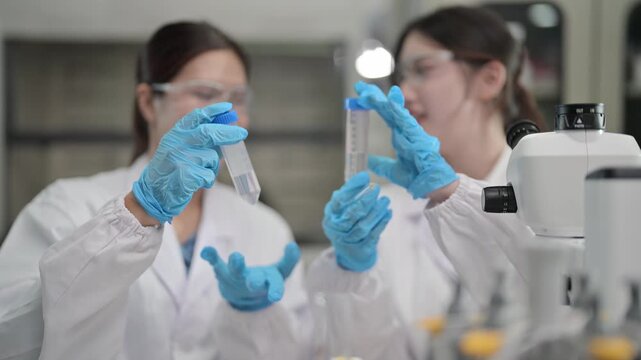 Lab assistants conduct experiments with test tubes in a busy laboratory during daytime hours