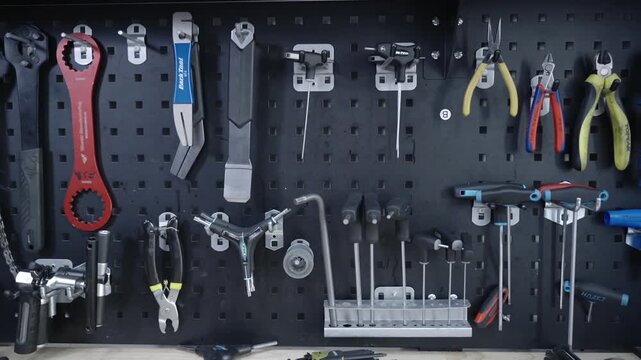 Detailed view of a professional bike mechanic workspace with various tools on a pegboard organizer. Precision engineering hardware, wrenches and custom equipment for bicycle overhaul and service.