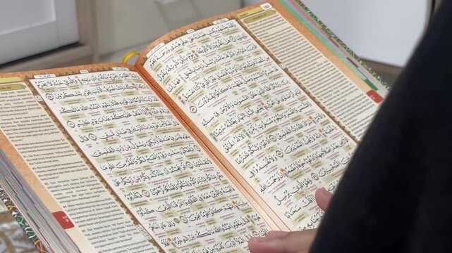 Muslim woman reading Al Quran book text with translation at home