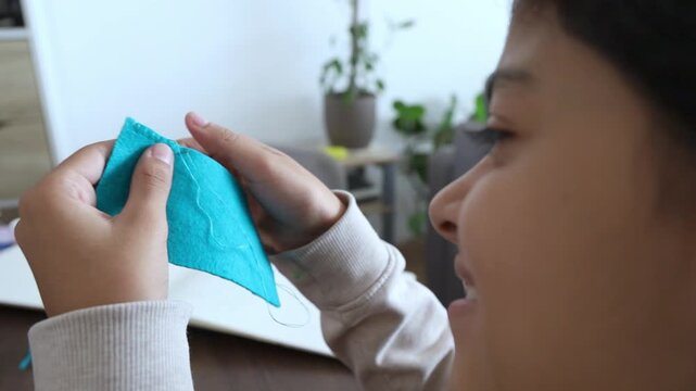 Happy Teenager Girl Learning To Sew With Needle And Thread At Home