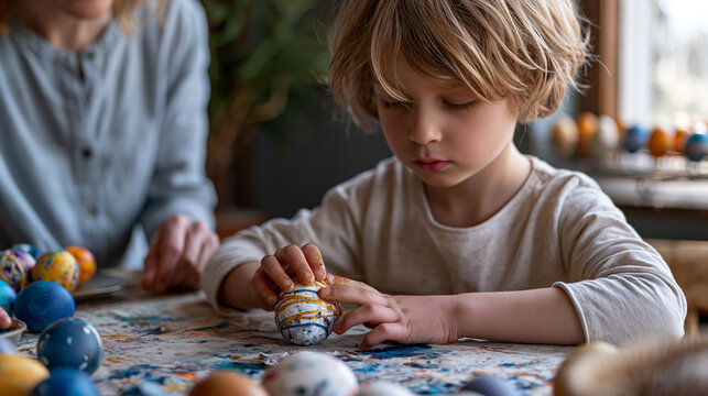 Crafting table covered in Easter egg supplies where an eight-year-old presses rubber band resist patterns onto a dyed egg surface, wet fingers smudging a decorated shell, a nearby