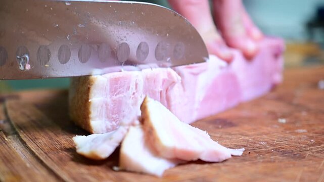 up close cutting ham, cutting board man close up of a knife slicing good chunk of ham cold cut meat